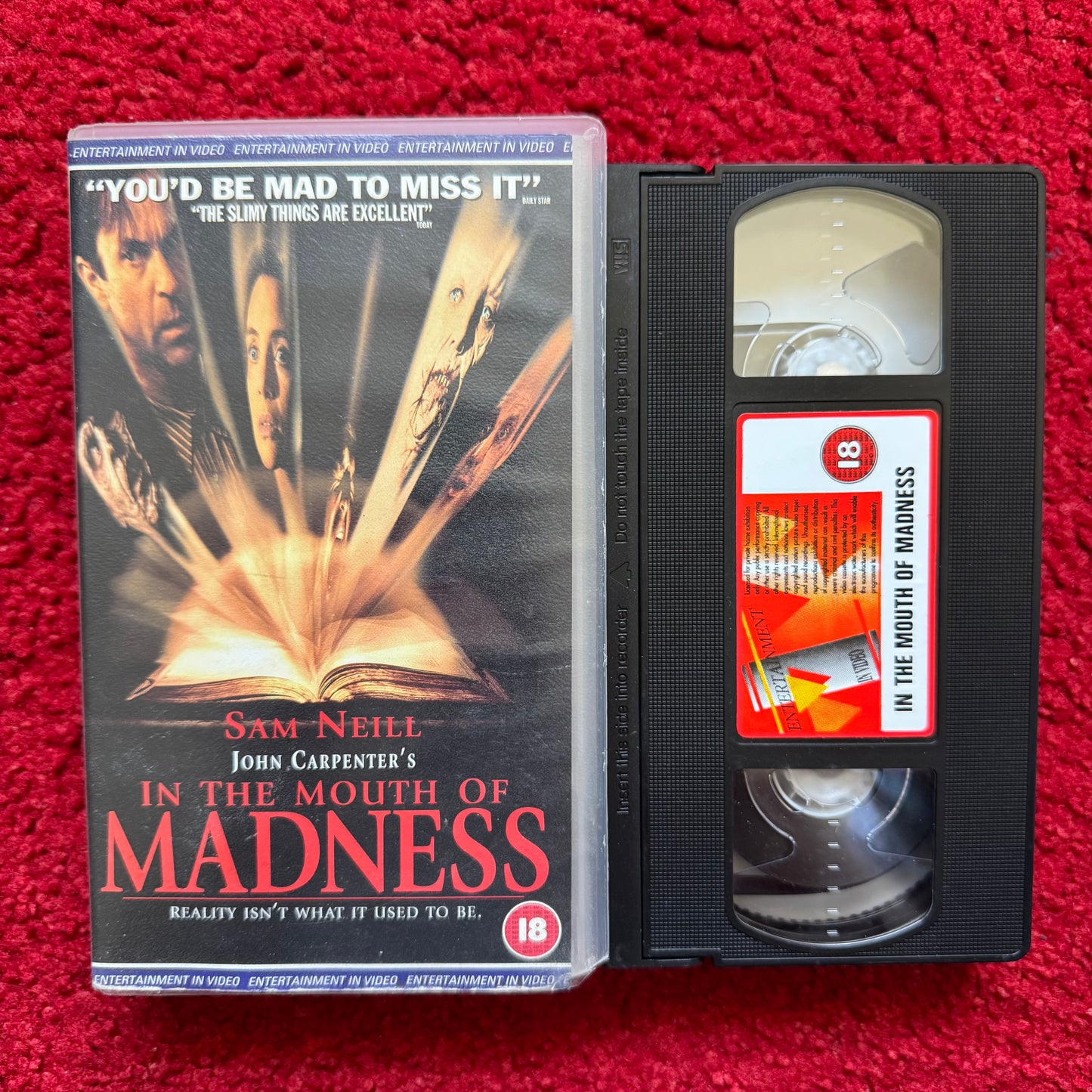 VHS tape of 'In the Mouth of Madness VHS' with cover on a red background
