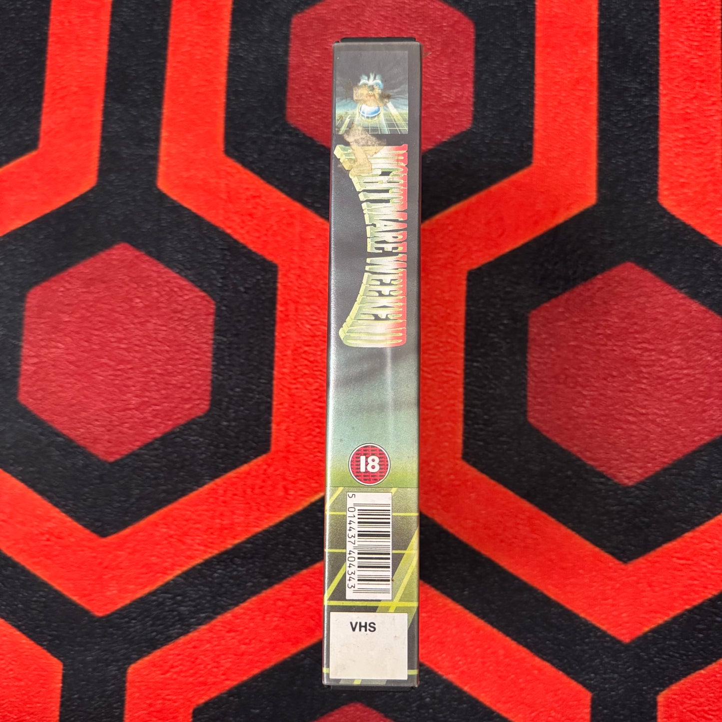 VHS tape with a barcode and '18' rating on a red and black patterned background