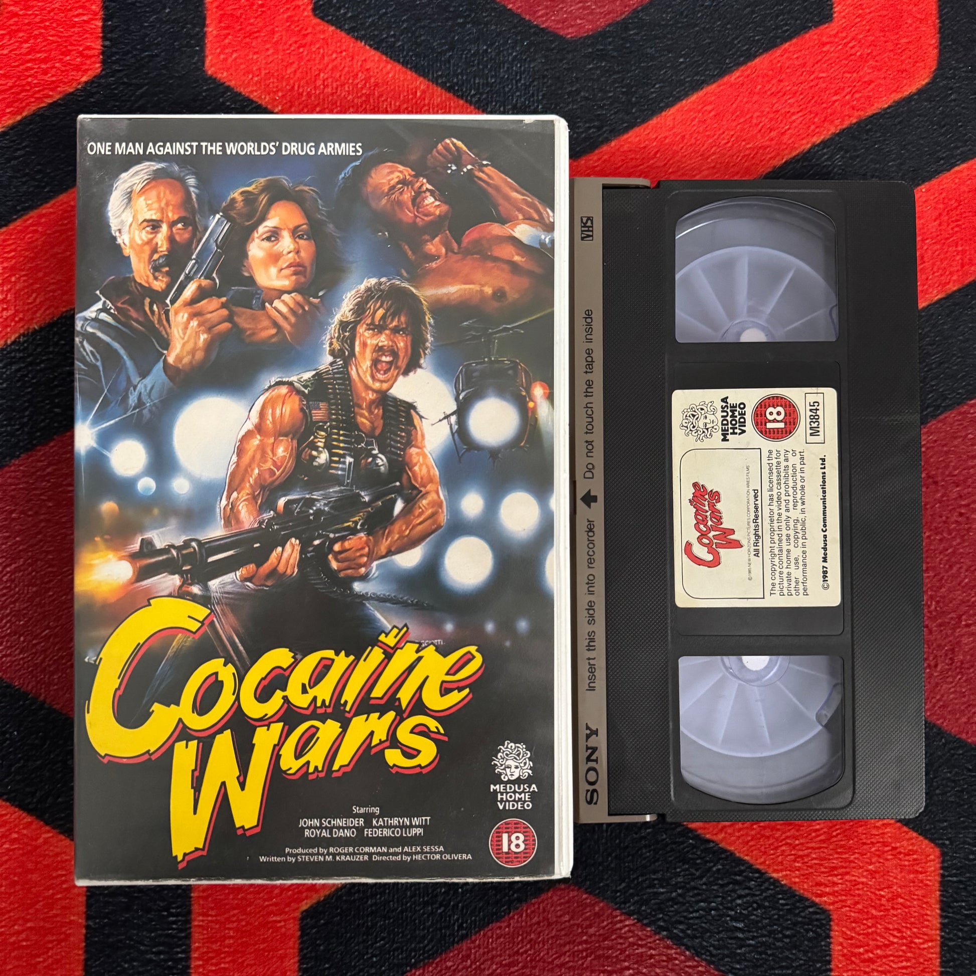 VHS tape of 'Cocaine Wars VHS' with movie poster on a red and black striped background