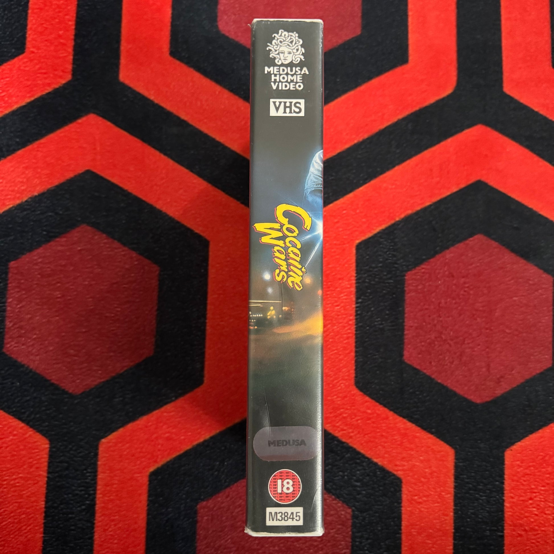 VHS tape with 'Cocaine Wars VHS' branding on a red and black patterned background