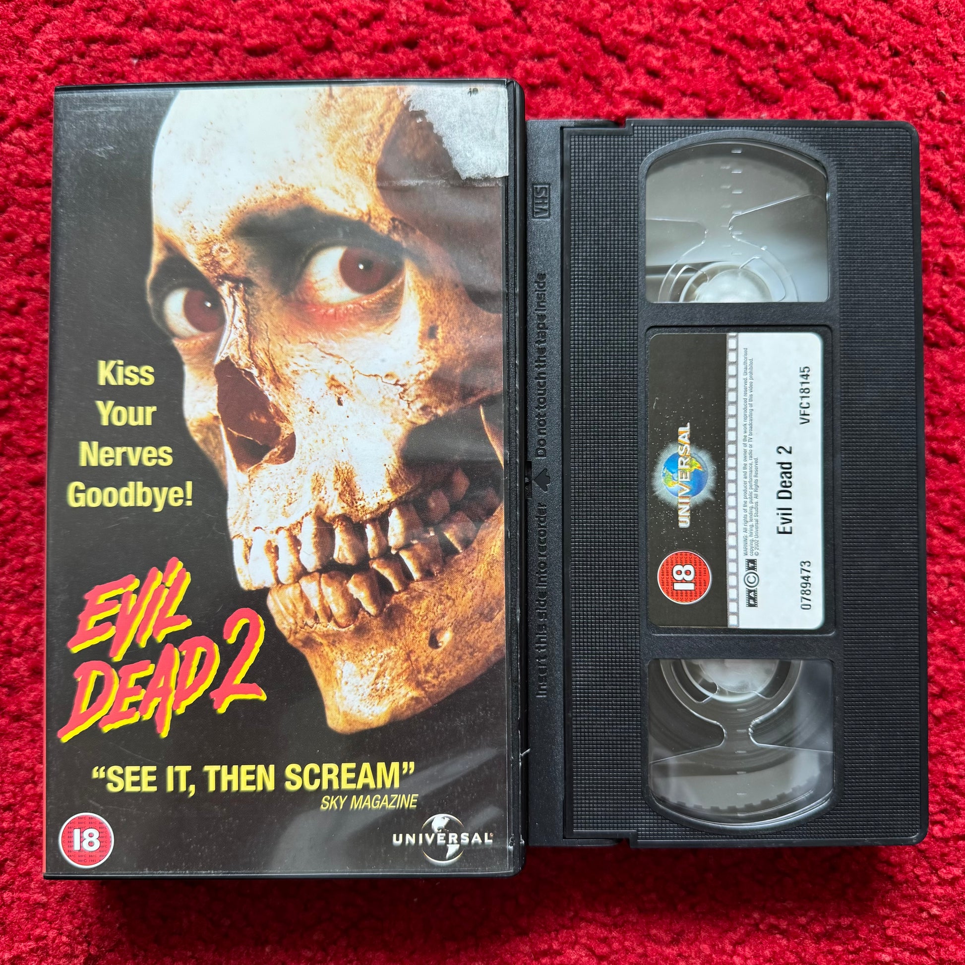 VHS tape of 'Evil Dead 2' with cover on a red background