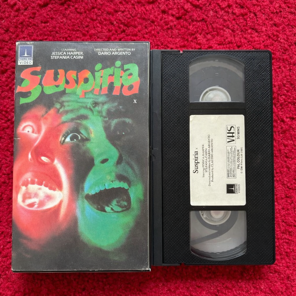 VHS tape of 'Suspiria' with its cover on a red background